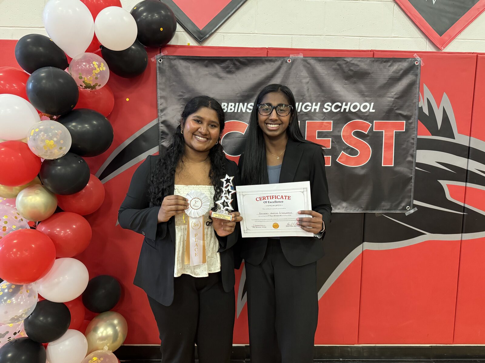 Ruhana Dhillion, Urba Adeel, and Minha Imran hold their 2nd Place Division 1 trophy, ribbon, and certificate in front of the SciFest banner.