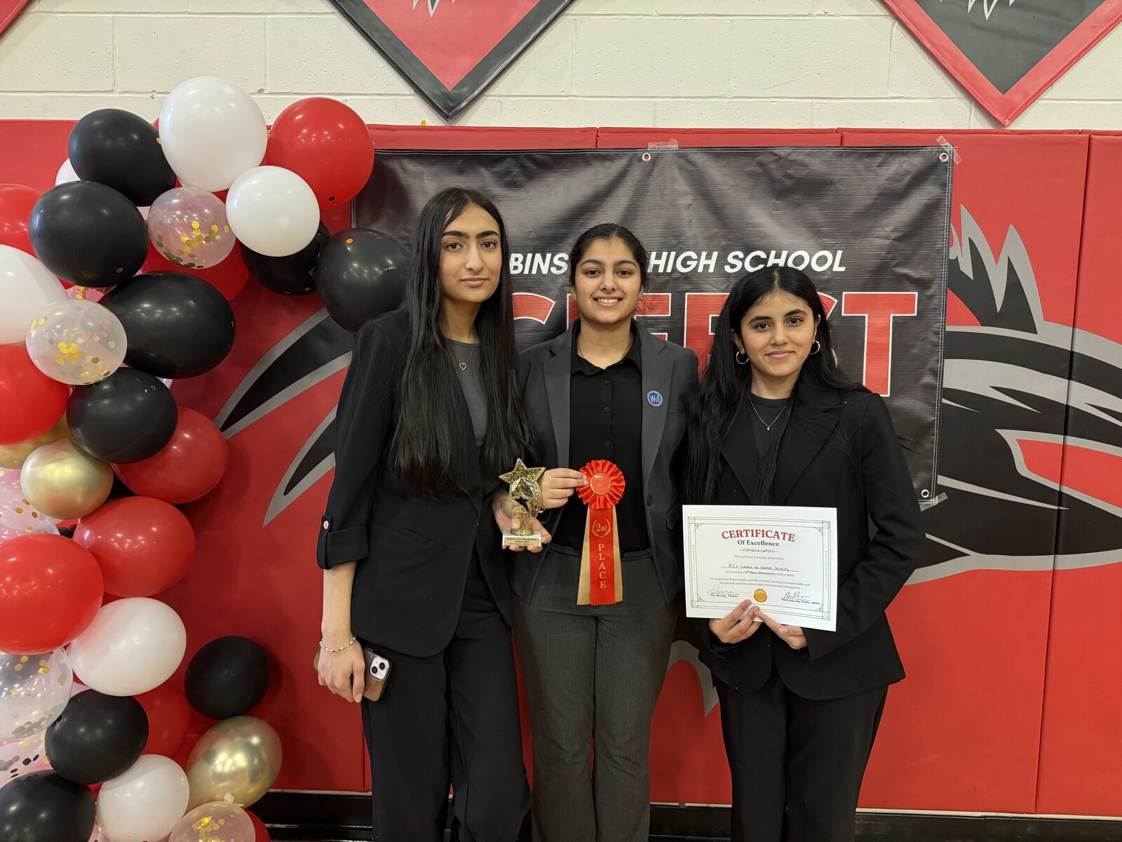 Swetha Subramanian and Mritula Boubalan hold their 3rd Place Division 2 trophy, ribbon, and certificate in front of the SciFest banner.
