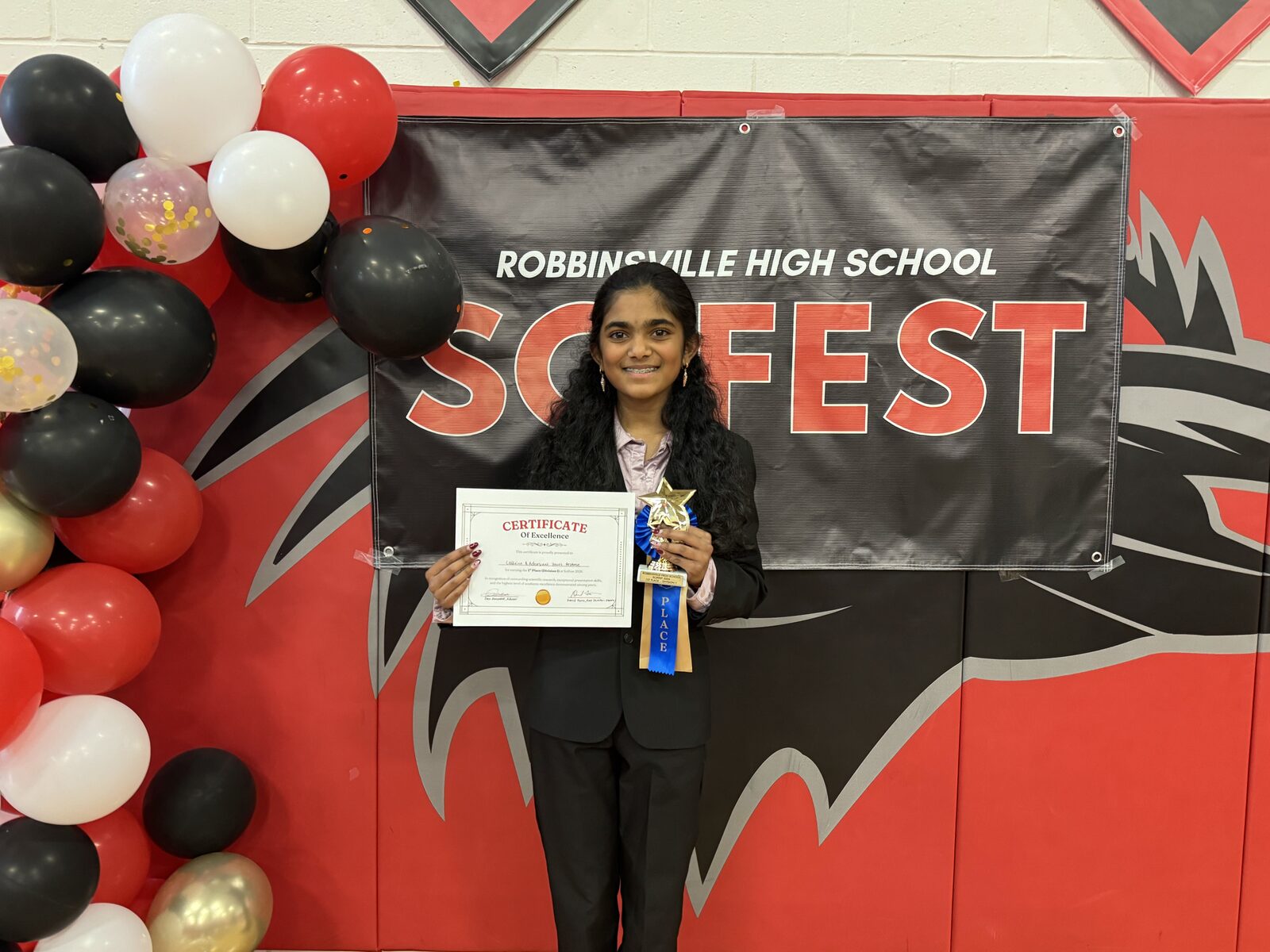Swetha Subramanian and Mritula Boubalan hold their Best Visual Display certificate in front of the SciFest banner.