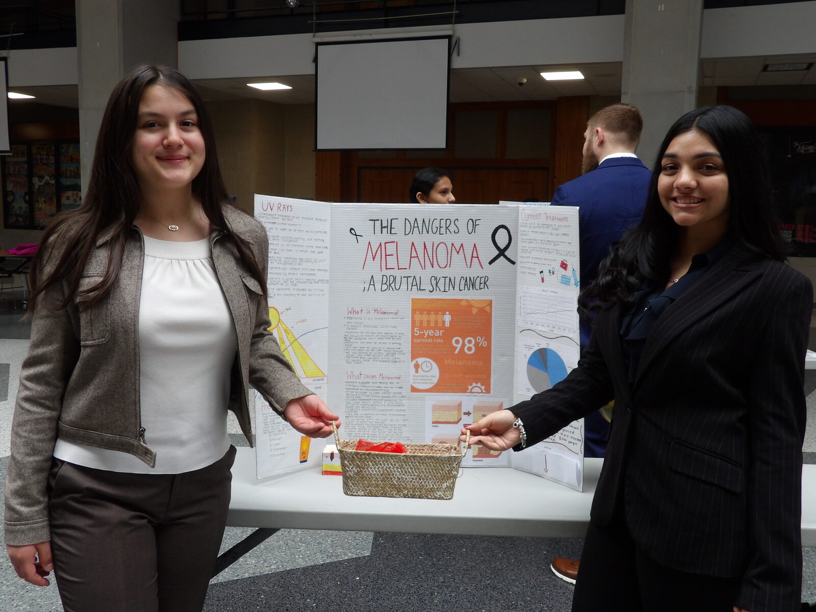 A SciFest 2026 presenter stands beside her research board.