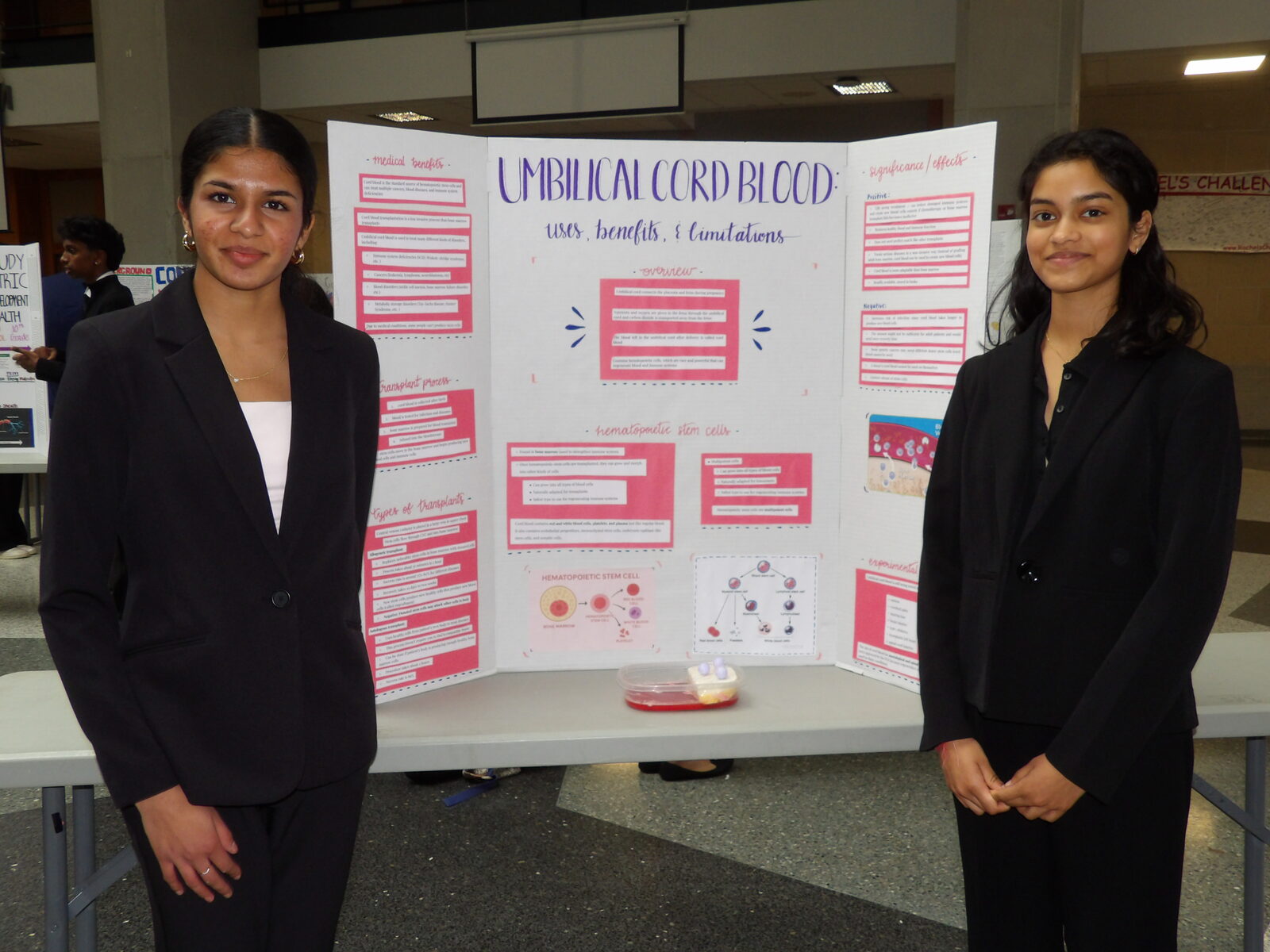 Two presenters stand beside their board on umbilical cord blood.